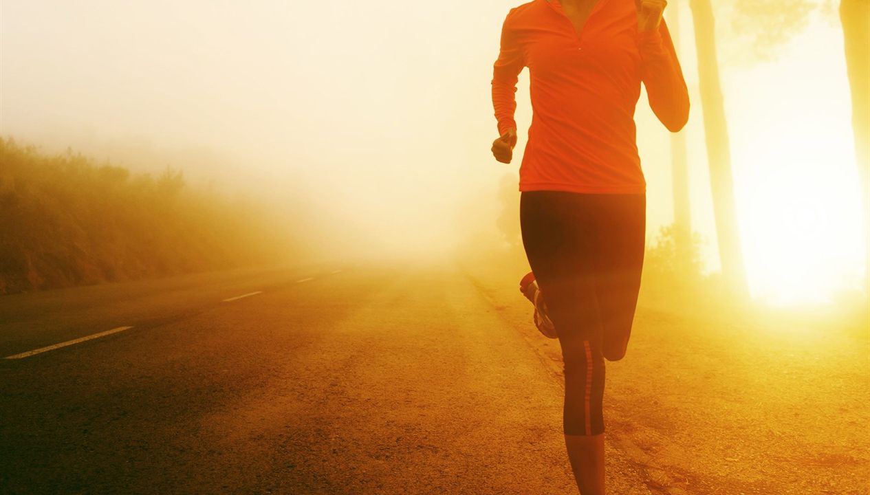 A runner on an open road at sunrise